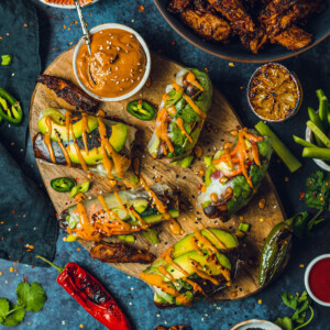 vegan summer rolls on a wooden chopping board with a peanut satay dip on the side