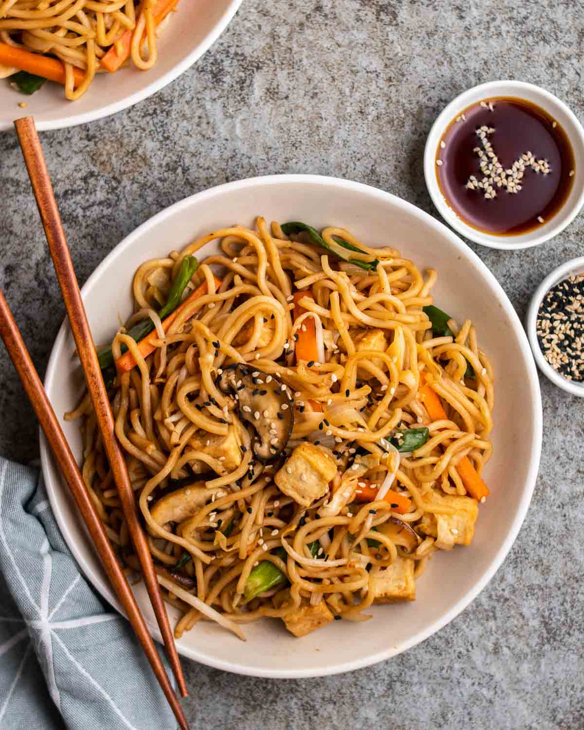 a white plate with vegan yakisoba on a stone table