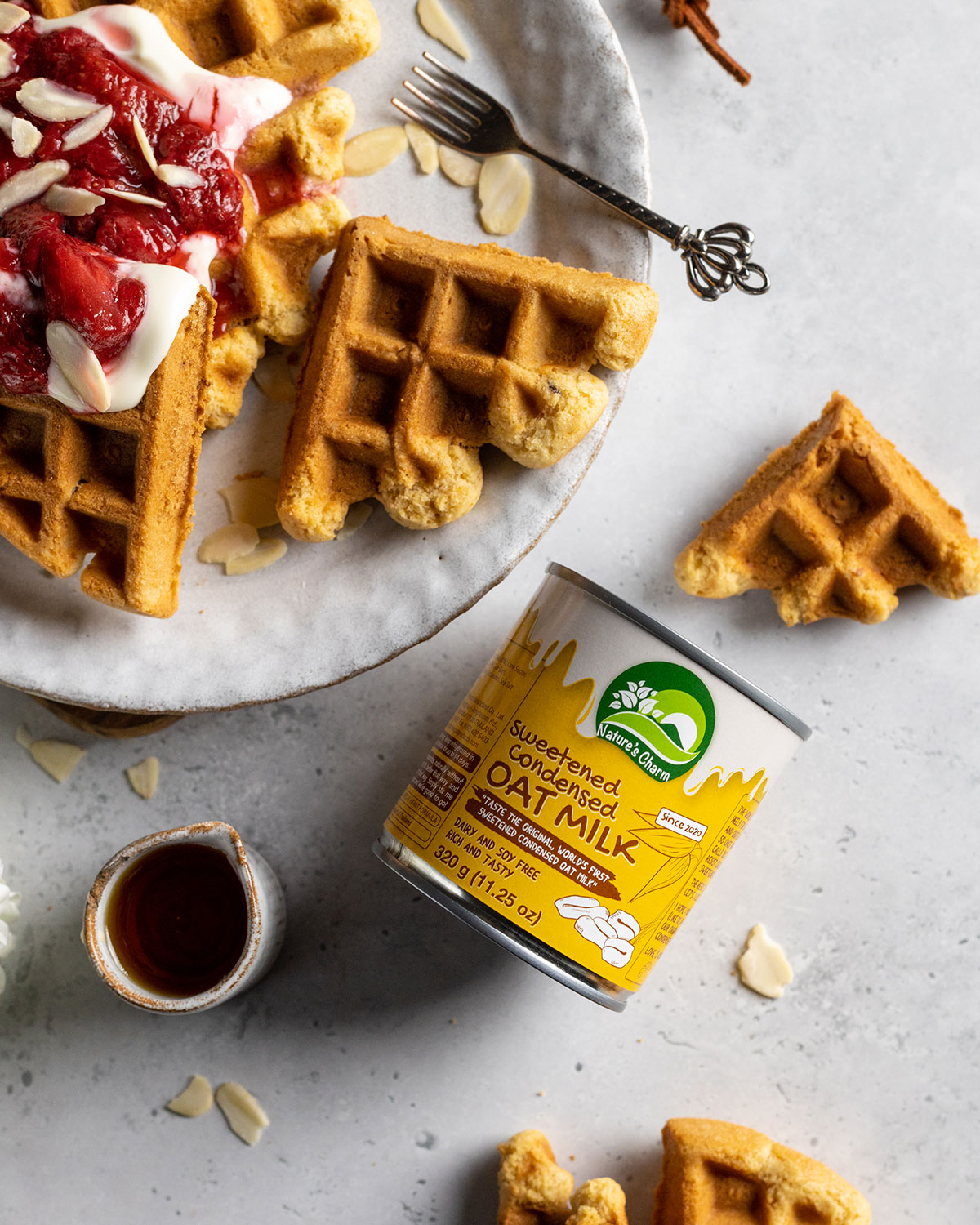 a can of vegan condensed milk by Nature's Charm on a white table next to a plate of waffles