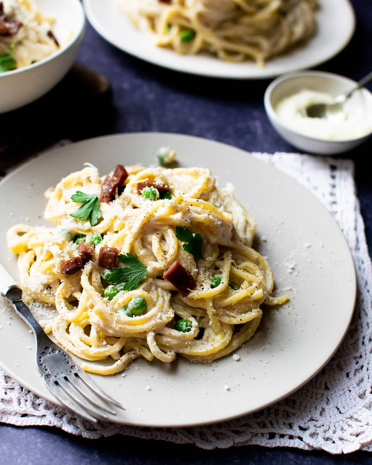 Vegan Carbonara pasta with a creamy sauce made from silken tofu, topped with crispy bacon bits and fresh parsley.