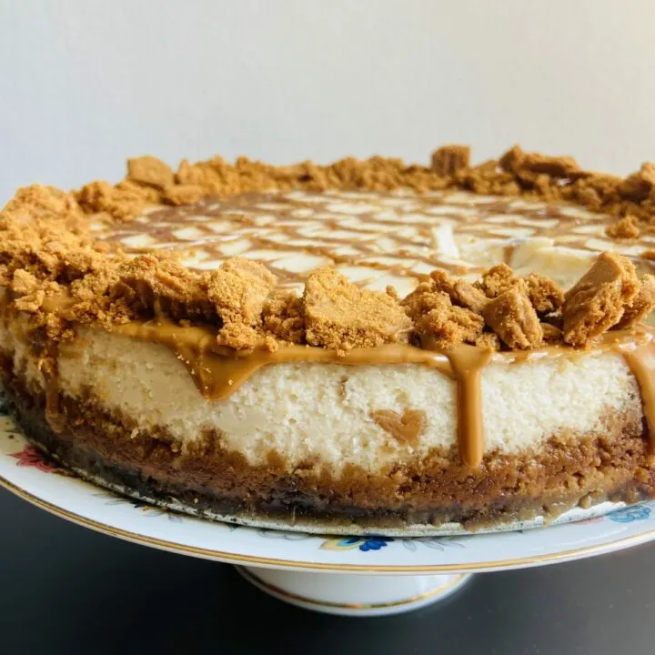 Vegan Biscoff Cheesecake topped with Biscoff cookies and fresh berries, sitting on a graham cracker crust. The filling is a creamy mixture of silken tofu and Biscoff cookies, creating a rich and indulgent dessert that's perfect for sharing.