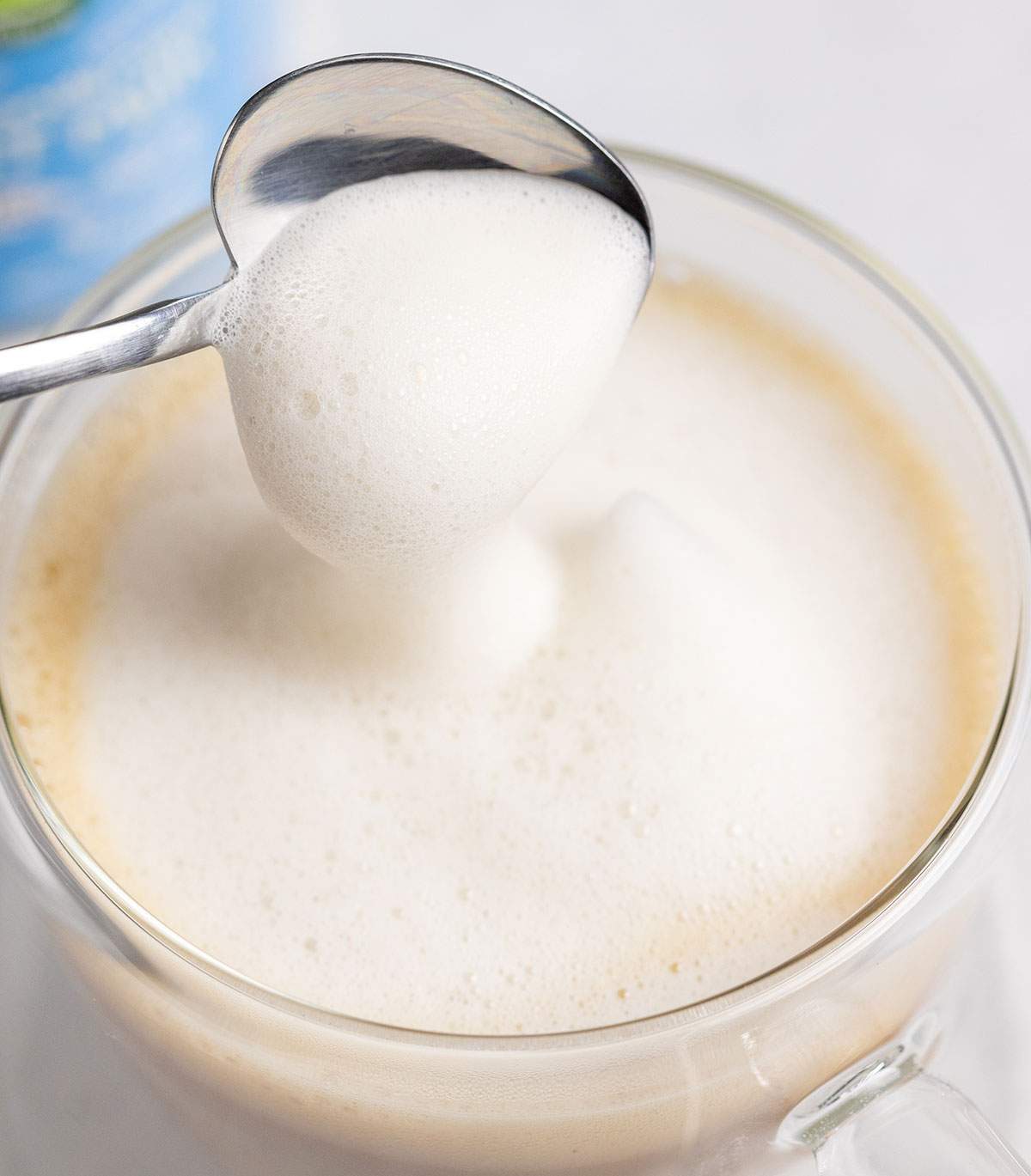 a spoon topping a spanish latte with frothed milk