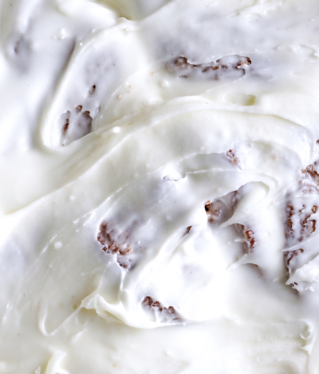 close up of frosting on baked cinnamon rolls