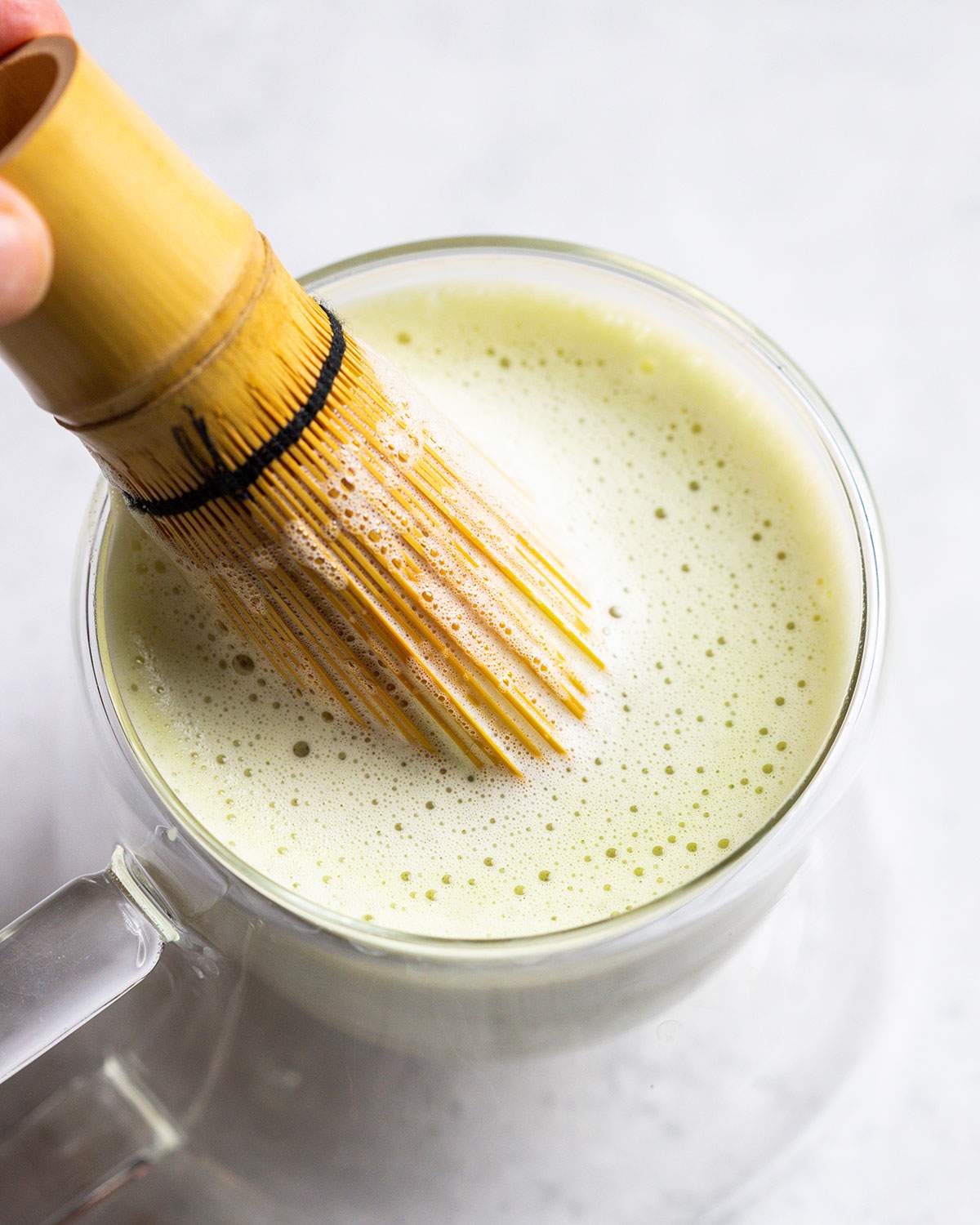 mixing vanilla matcha latte with a traditional matcha whisk