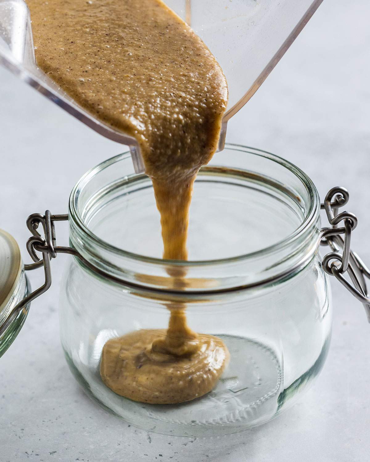 pouring brazil nut butter into a glass jar