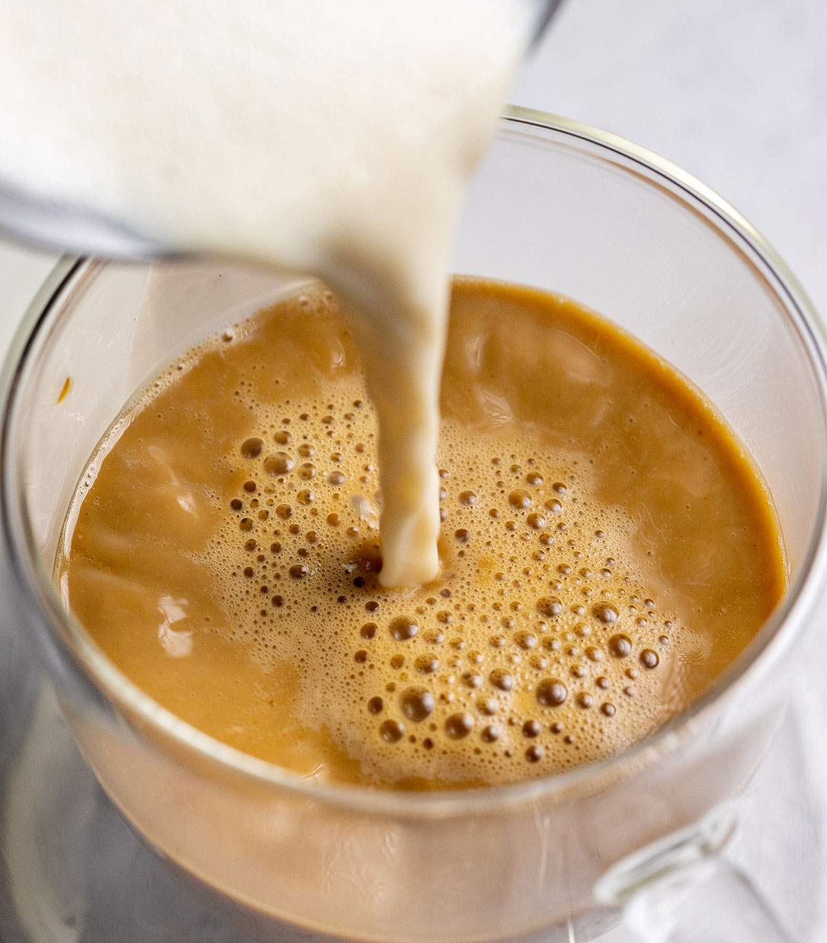pouring frothed milk onto coffee