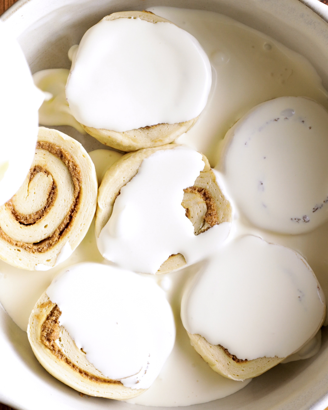 pouring heavy cream onto cinnamon rolls