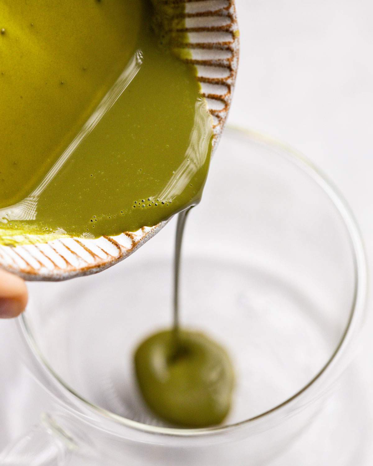 pouring matcha paste into a glass cup