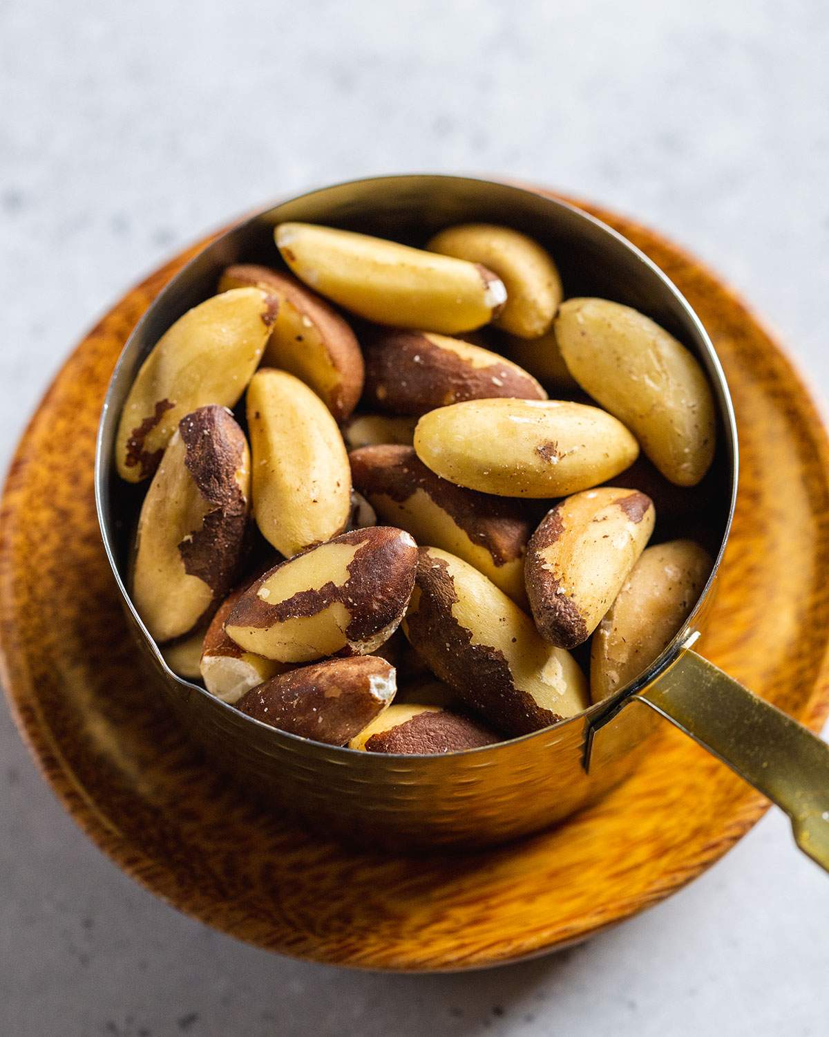 Raw brazil nuts in a measuring cup.