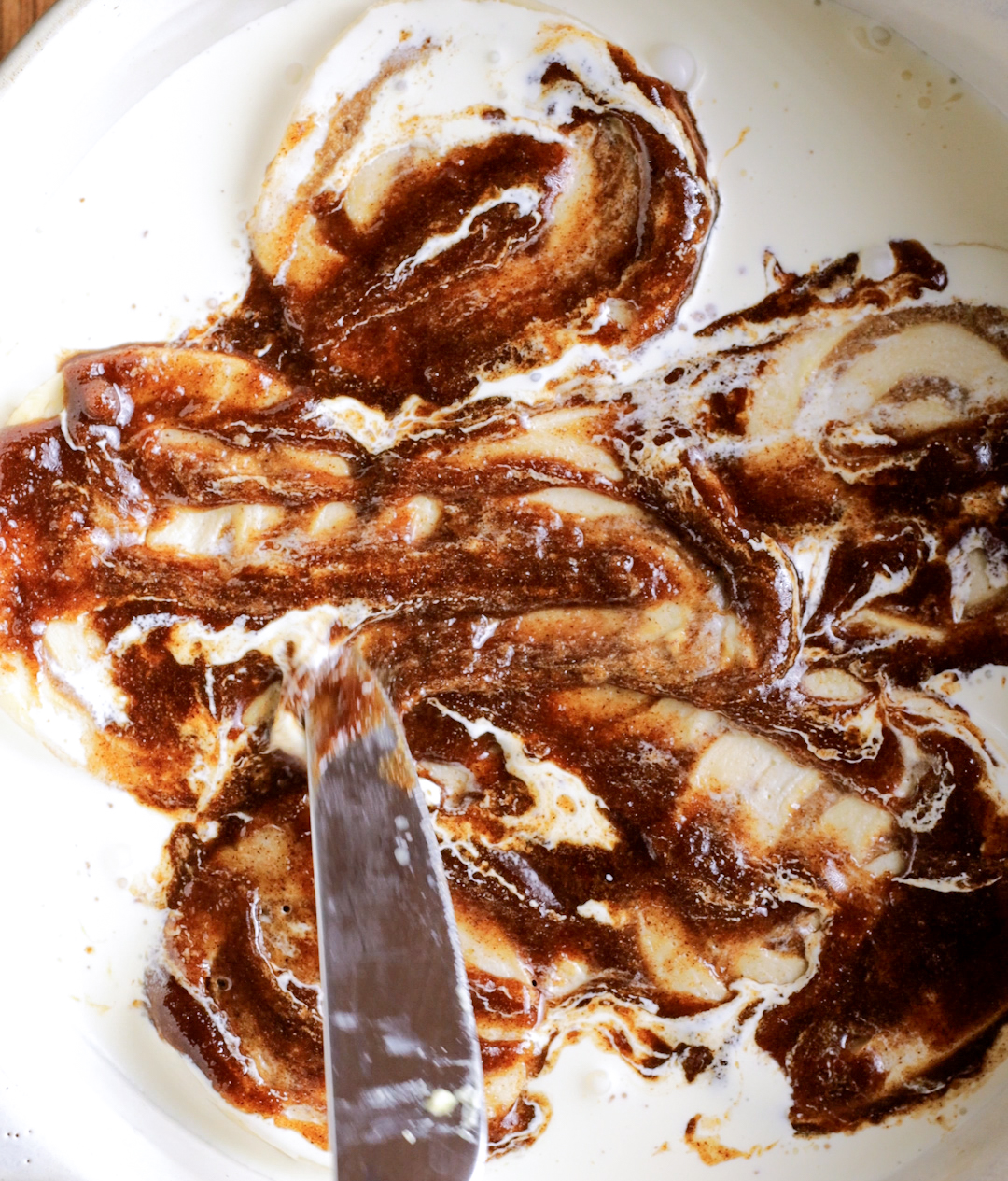 spreading cinnamon sugar mix over cinnamon rolls in an oven dish