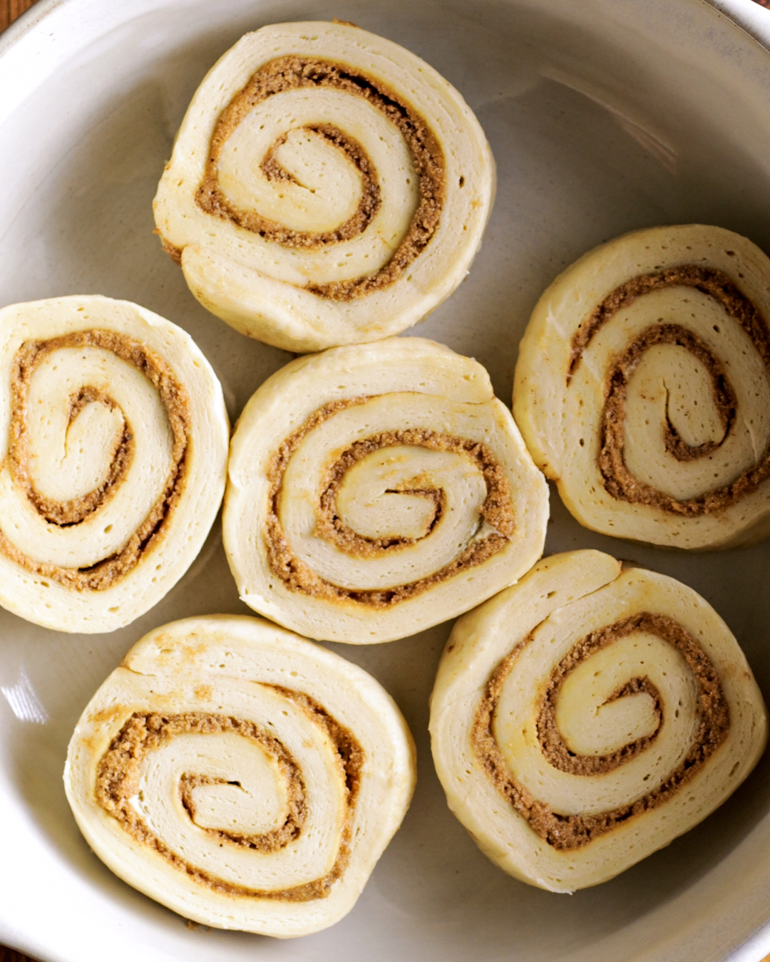 unbaked cinnamon rolls in a round oven dish