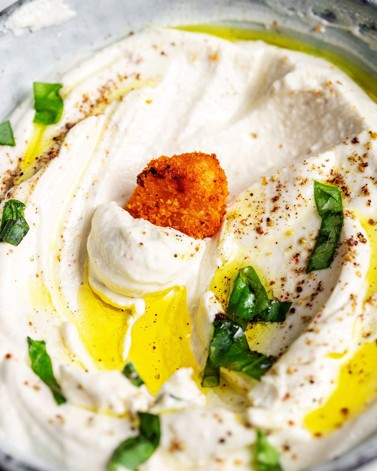 A crispy air fryer gnocchi being dipped into a bowl full of vegan whipped cream cheese.