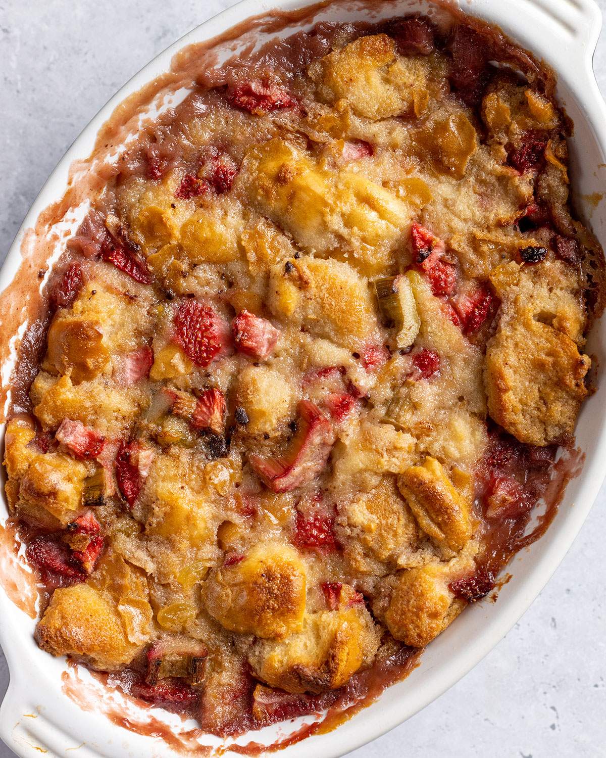 Strawberry and Rhubarb bread pudding in a white oven dish after baking.