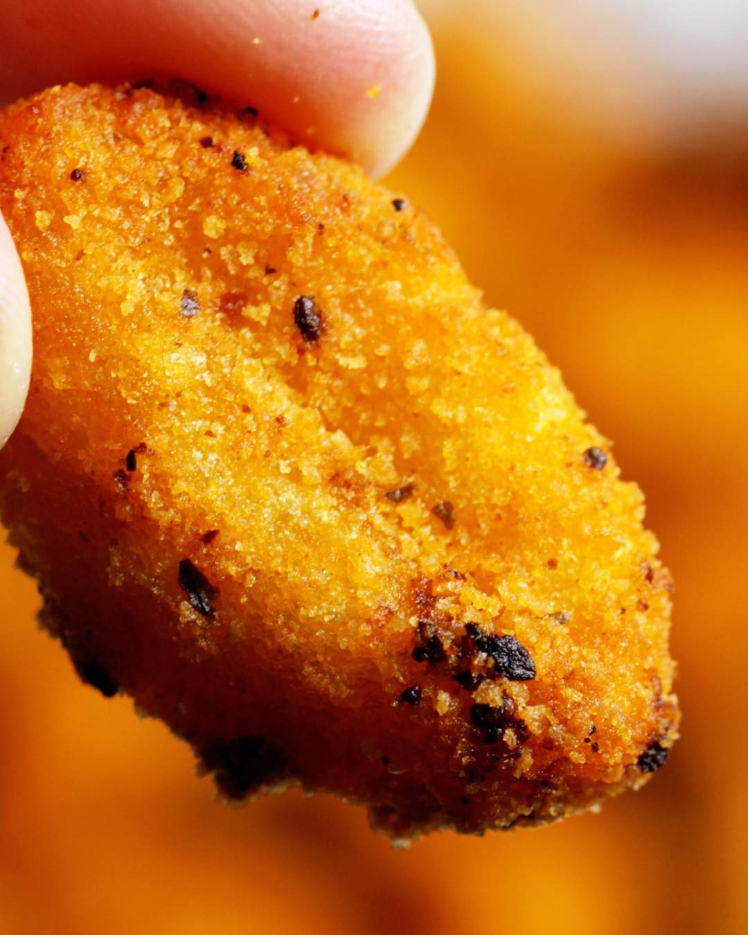 Close up of a hand holding an air fryer gnocchi.