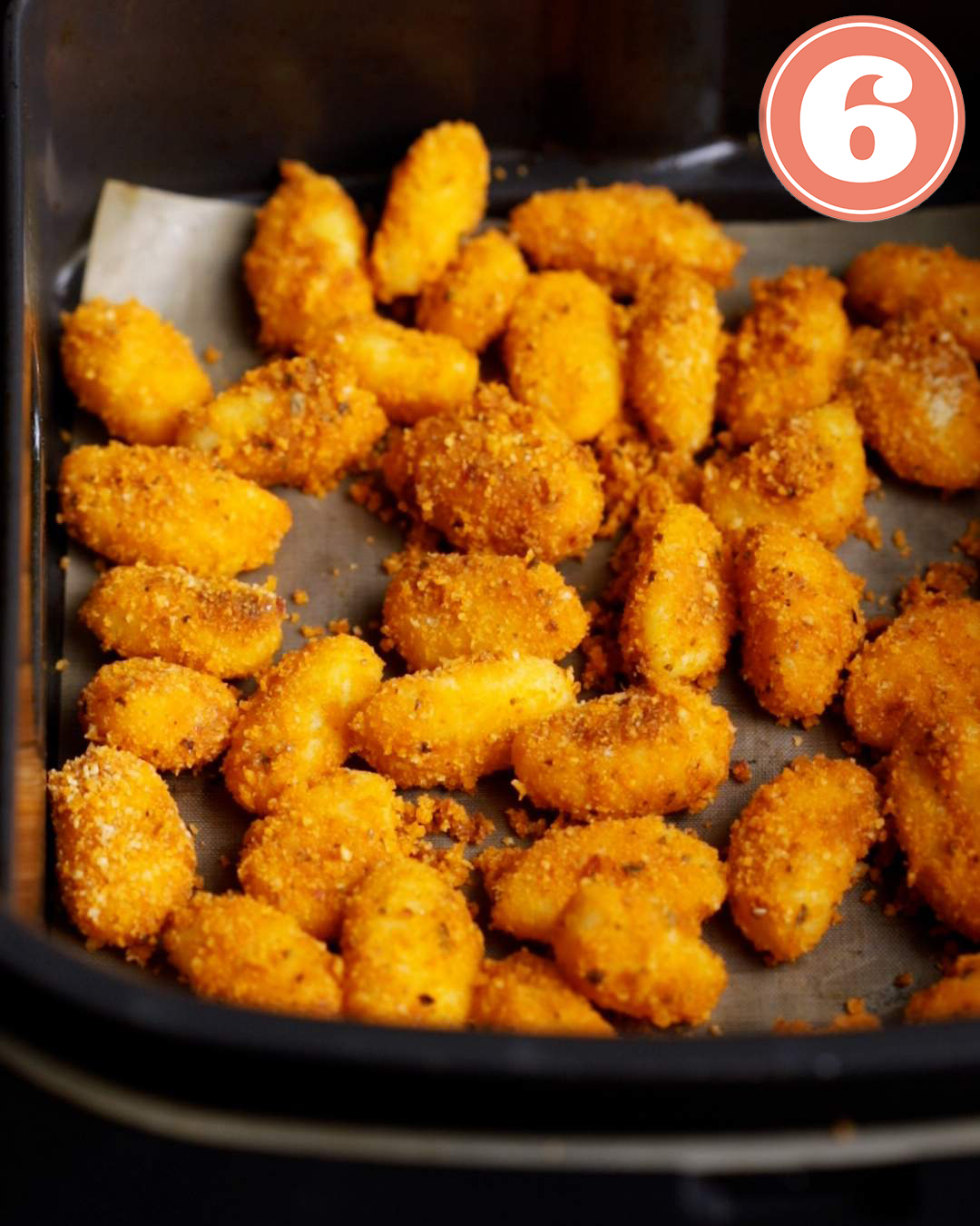 Crumb coated gnocchi in an air fryer in a single layer.