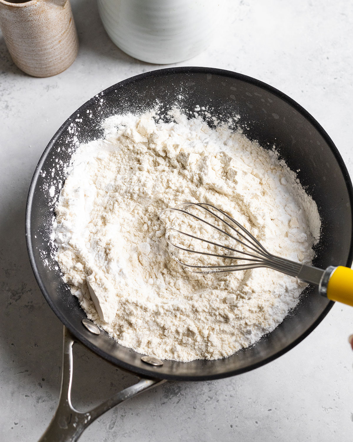 Dry ingredients for vegan pork belly fat being whisked in a black frying pan.