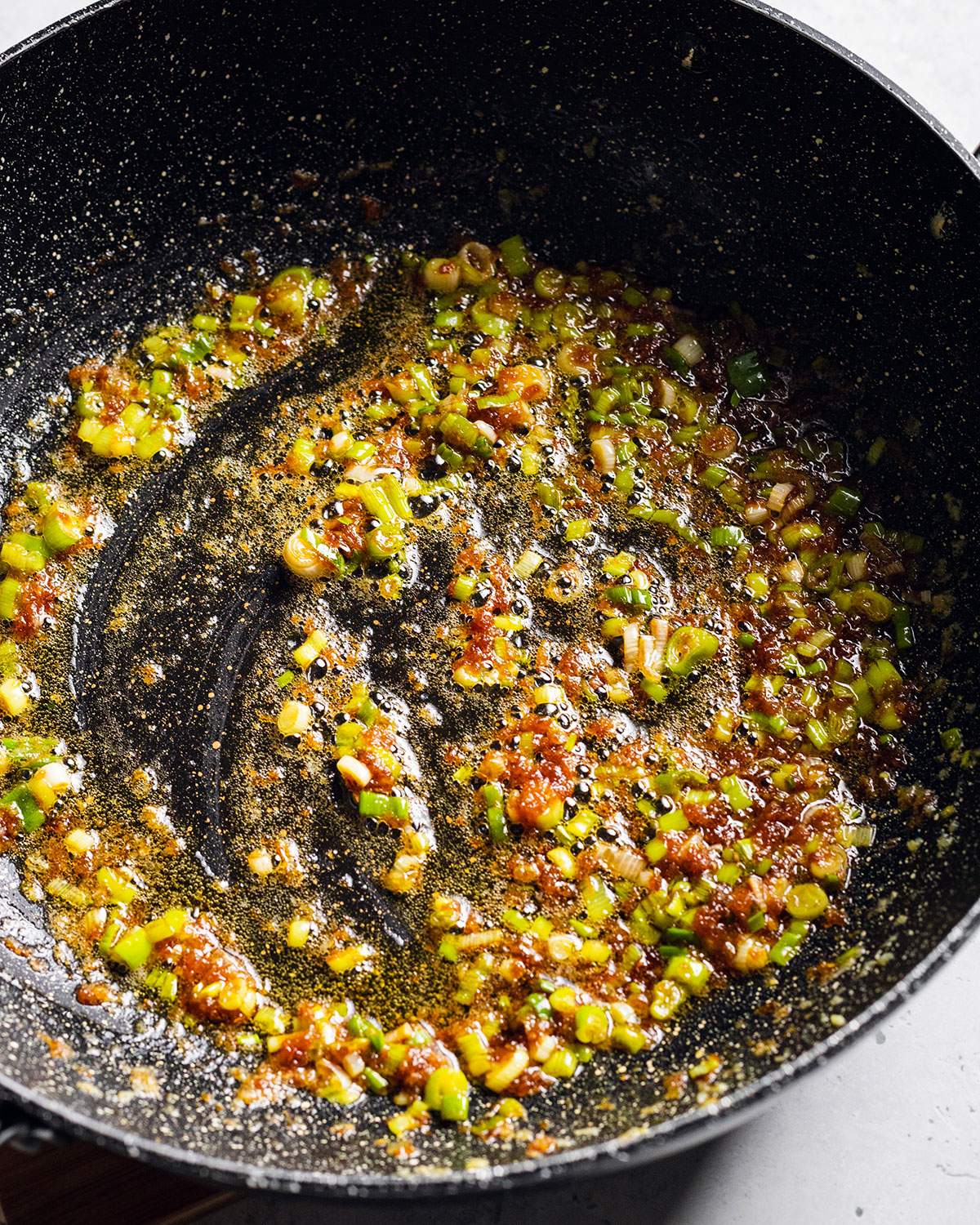 Frying scallions and aromatics in a wok.