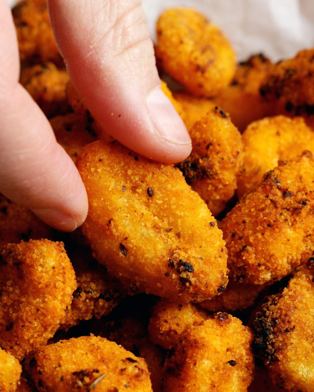 Hand picking up an air fryer gnocchi.