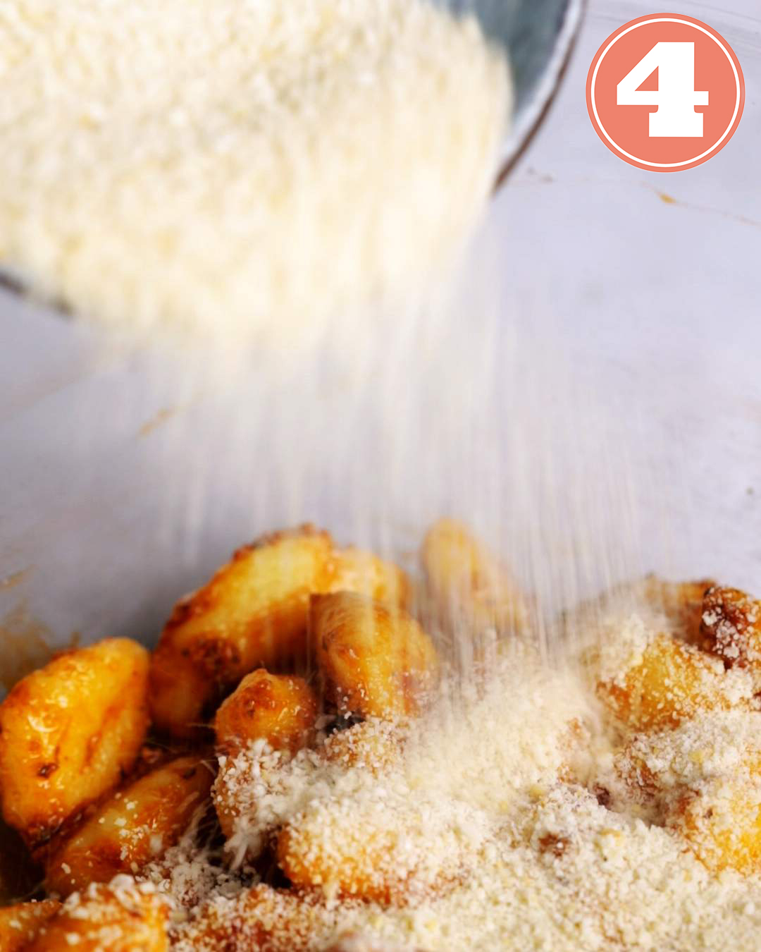 Pesto coated gnocchi being sprinkled with breadcrumbs.