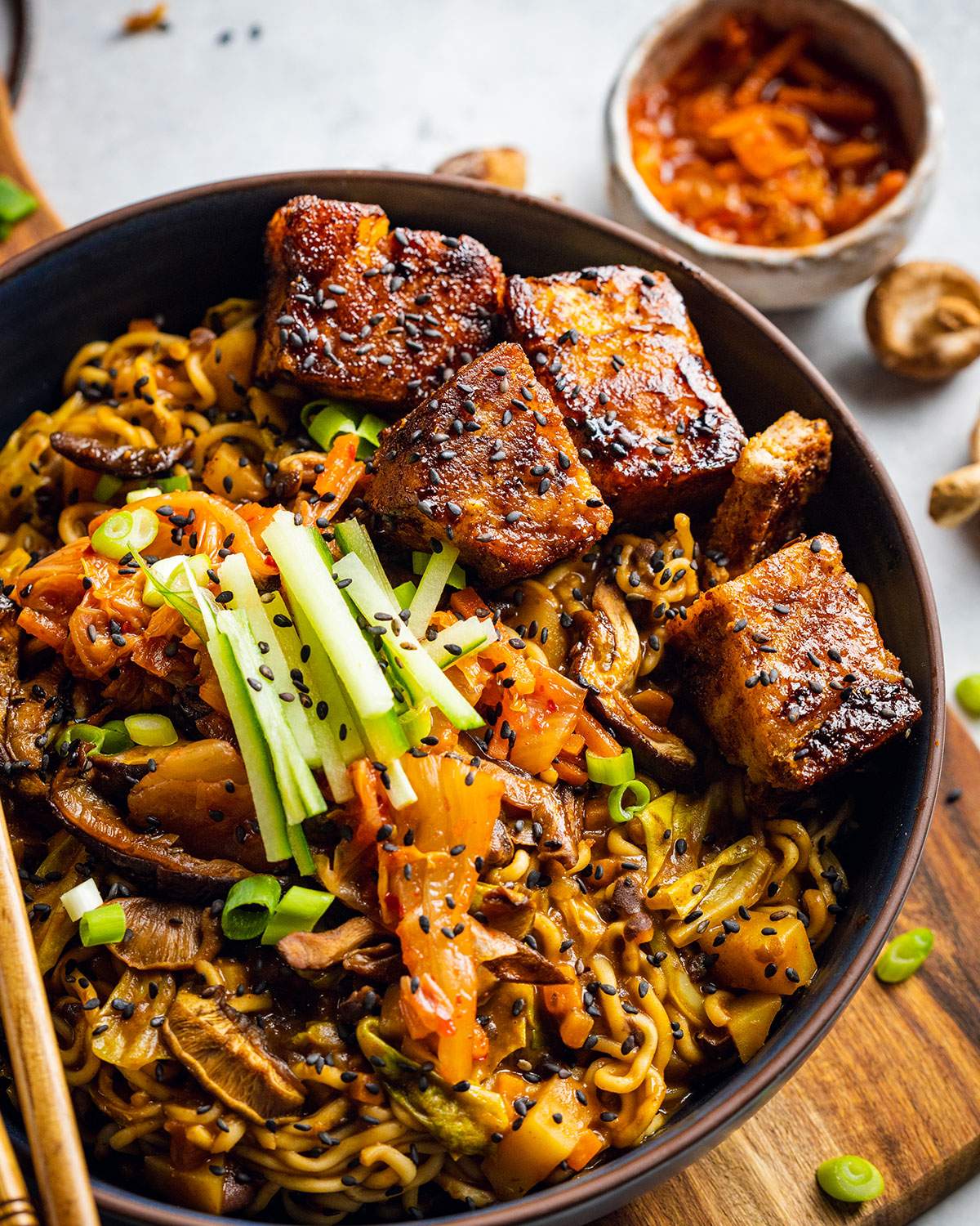 A bowl filled with vegan black bean ramen with vegan pork belly on top.