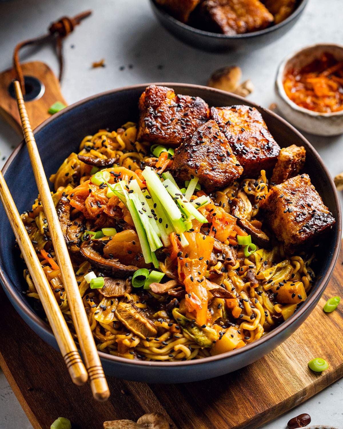 A bowl filled with vegan black bean ramen with vegan pork belly on top and chopsticks on the side.