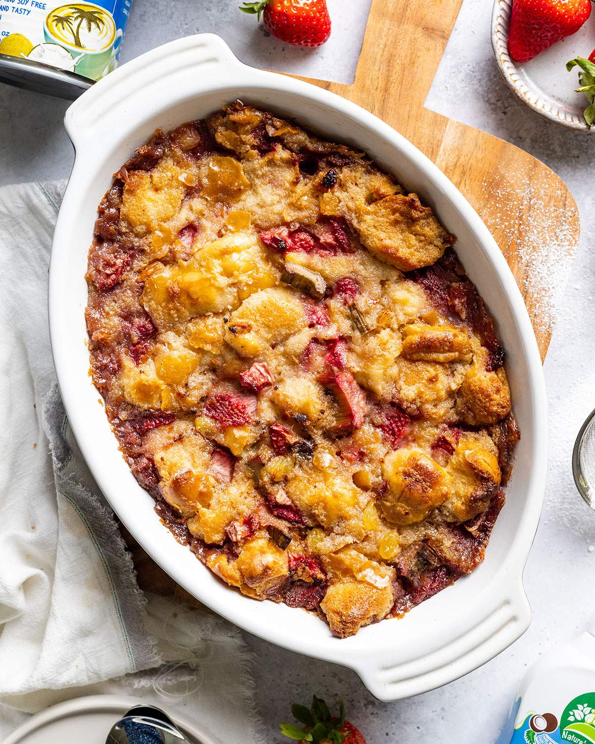 Vegan Baked Bread Pudding in an oven dish sitting on a wooden board on a white table.