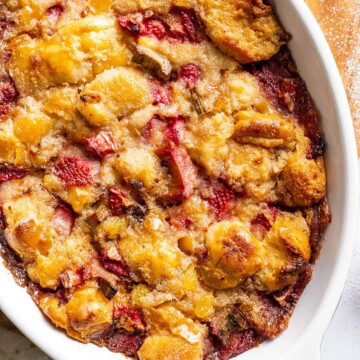 Baked Vegan bread pudding up close with strawberries and rhubarb visible.