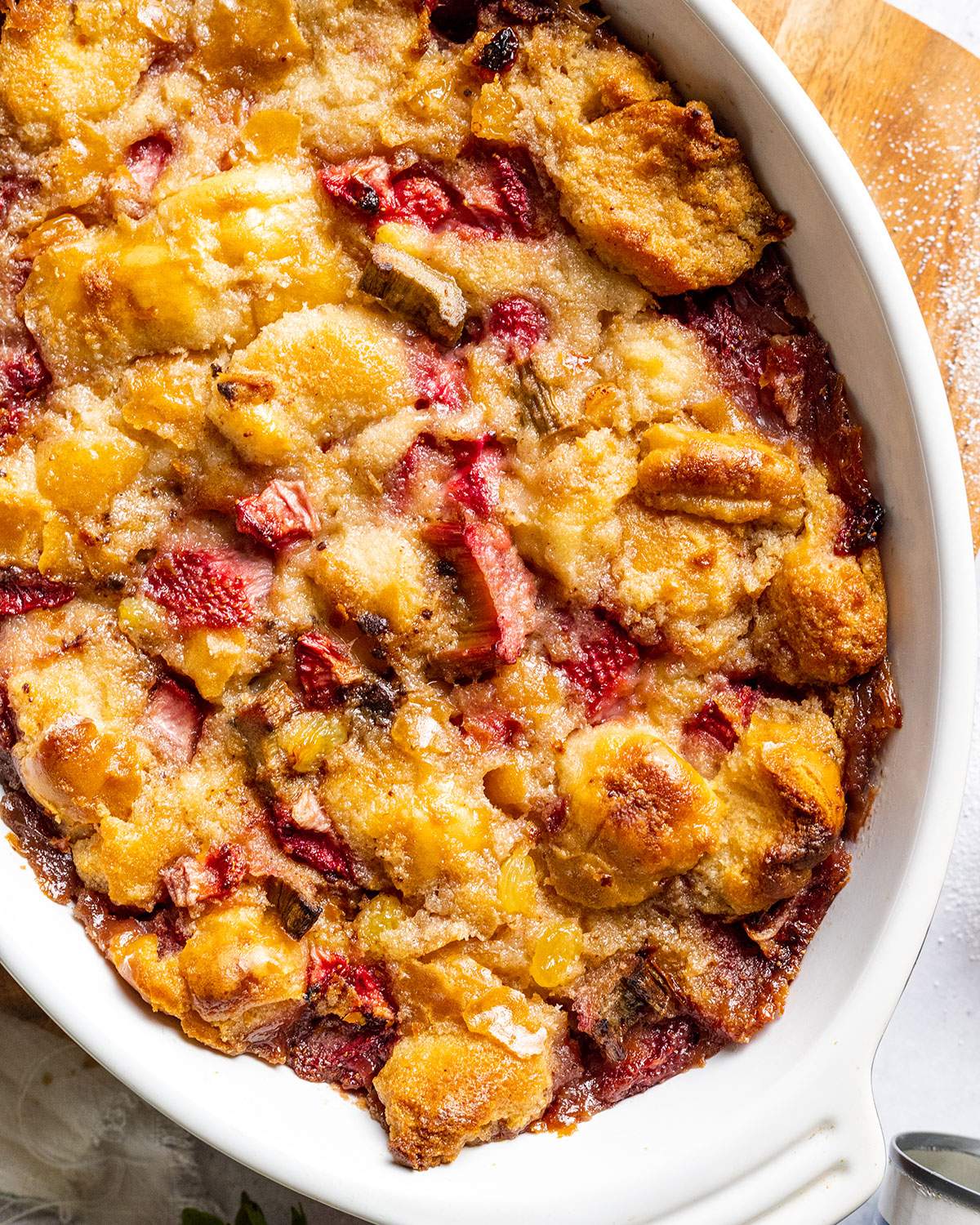 Baked Vegan bread pudding up close with strawberries and rhubarb visible.