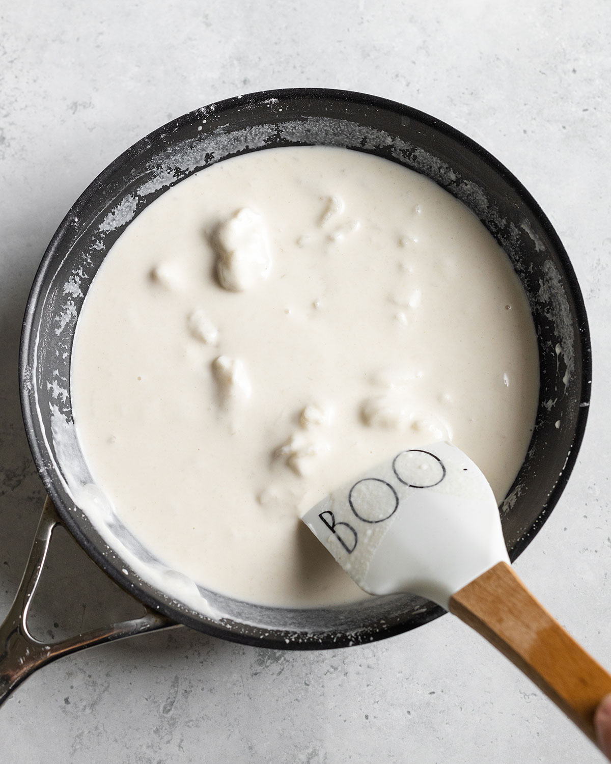 Vegan fat layer for pork belly in a black pan with a spatula stirring.