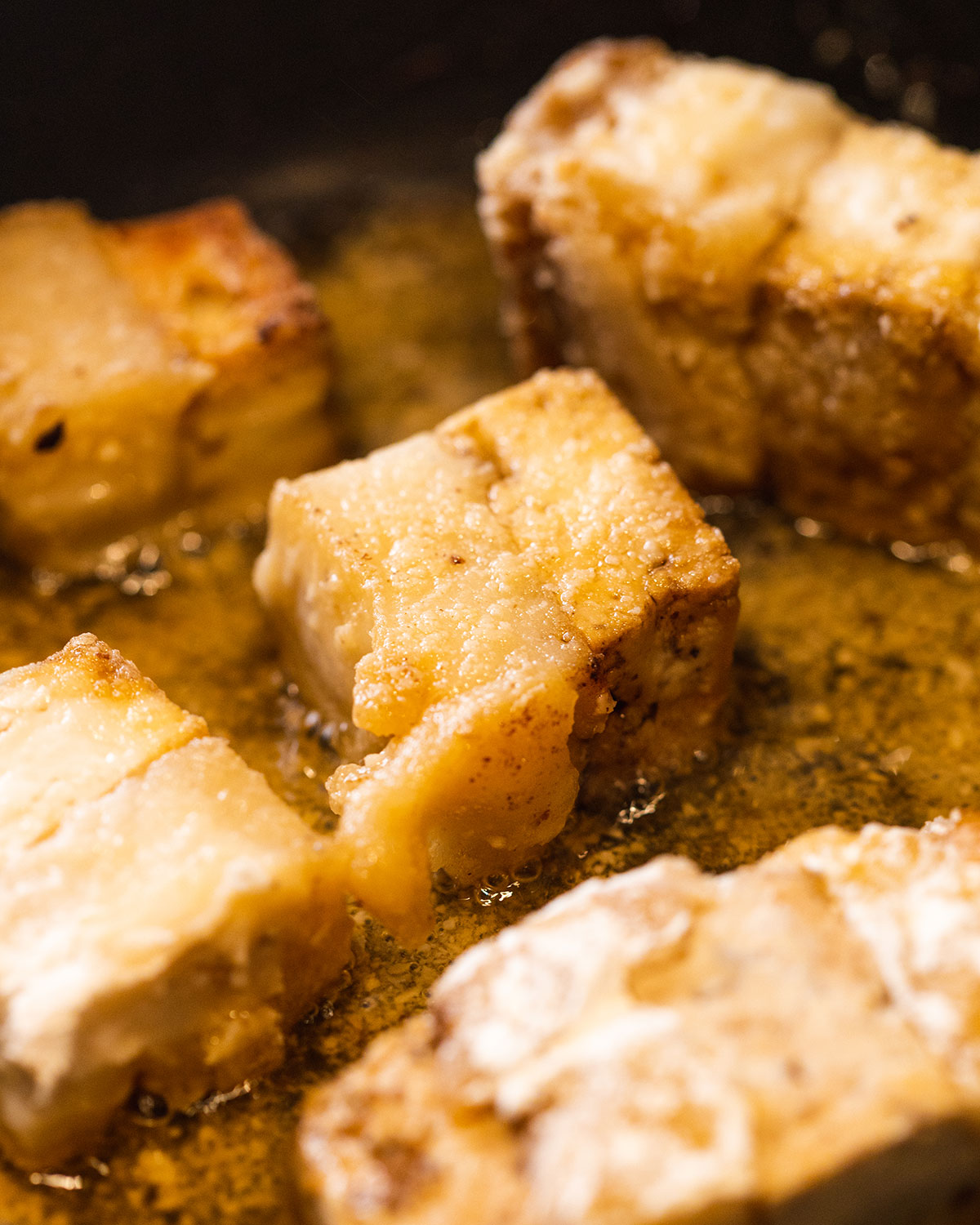 A piece of vegan pork belly up close frying in hot oil.