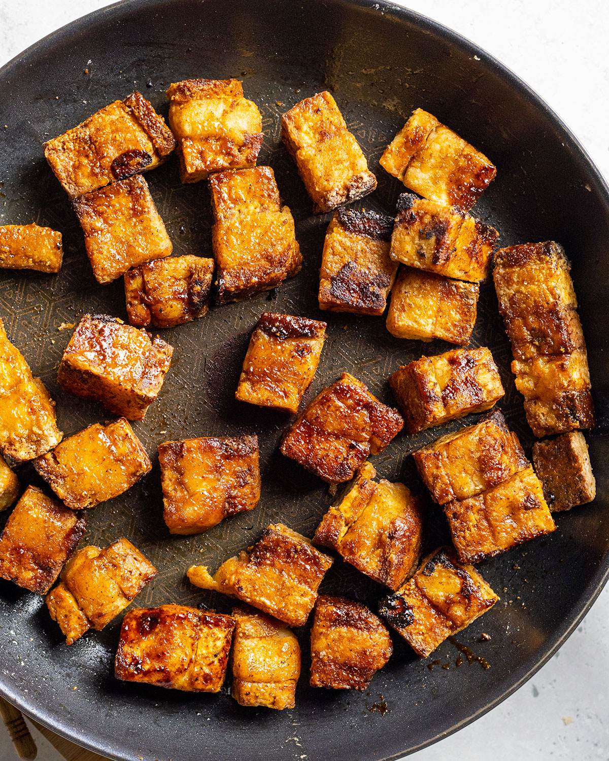 A black frying pan filled with fried vegan pork belly.