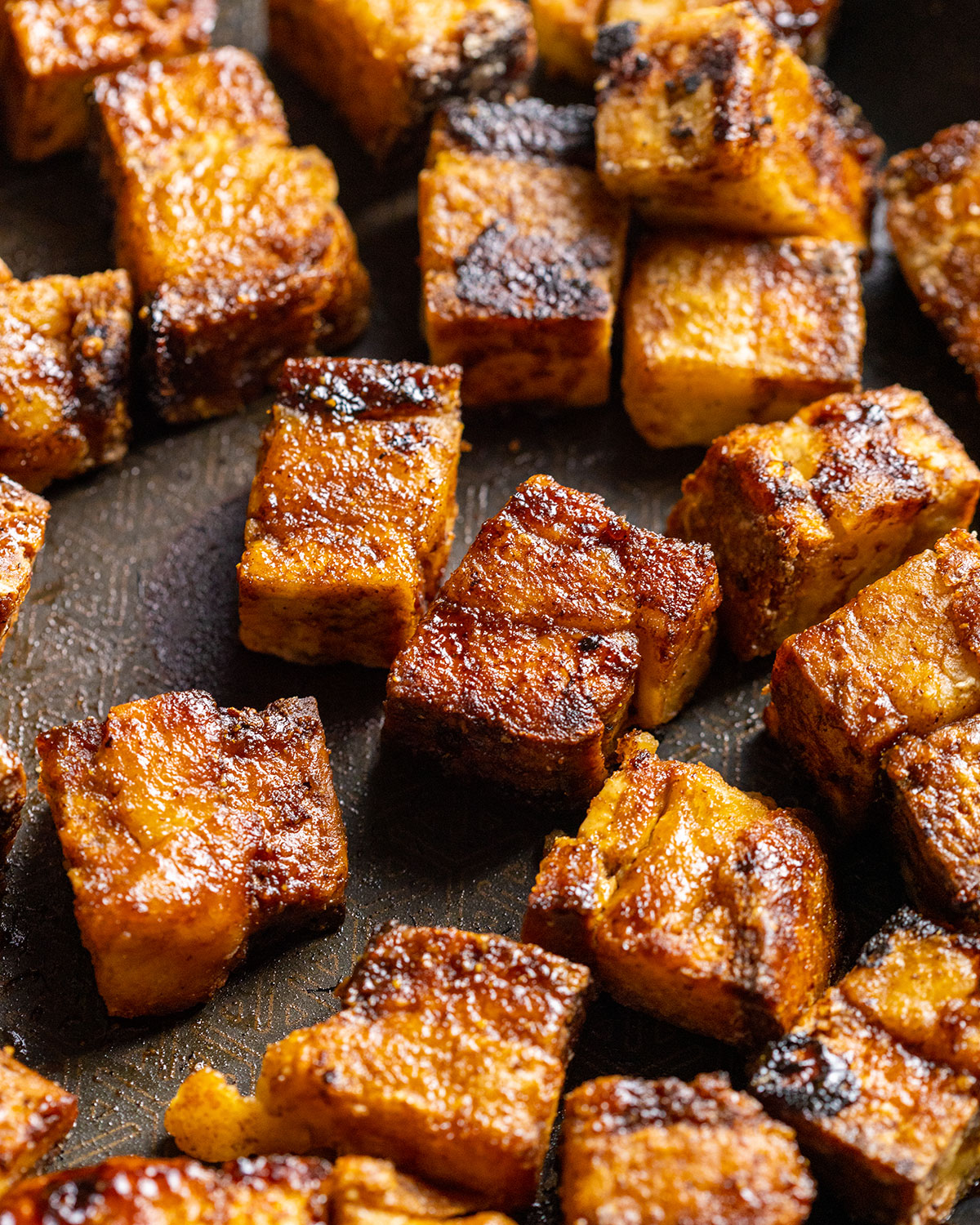 A frying pan filled with fried vegan pork belly pieces up close.