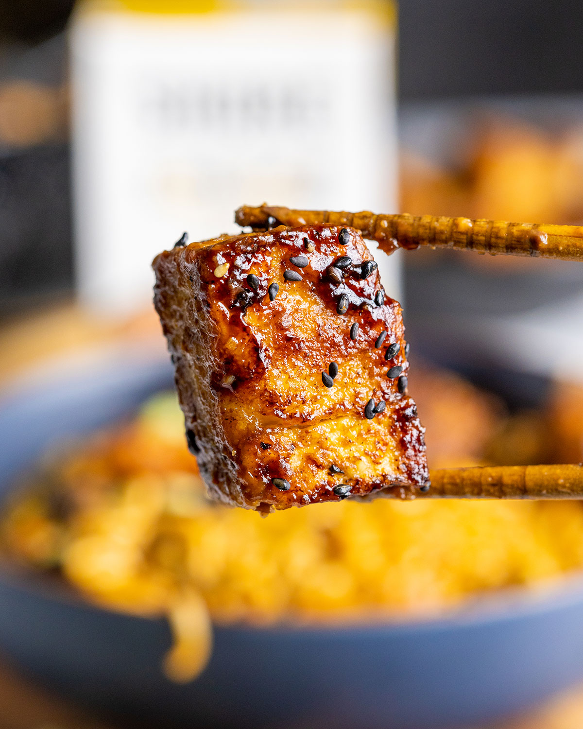 Wooden chopsticks holding a piece of vegan pork belly into the camera.