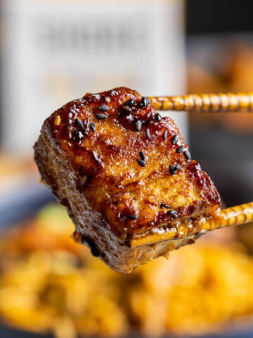 Thumbnail for vegan pork belly recipe with chopsticks holding a delicious vegan pork belly piece up close.