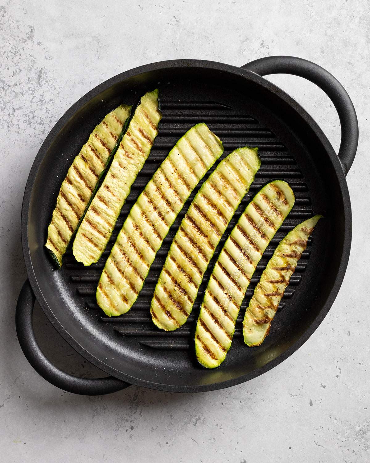 Grilled zucchini slices in a griddle pan with the grill lines visible.