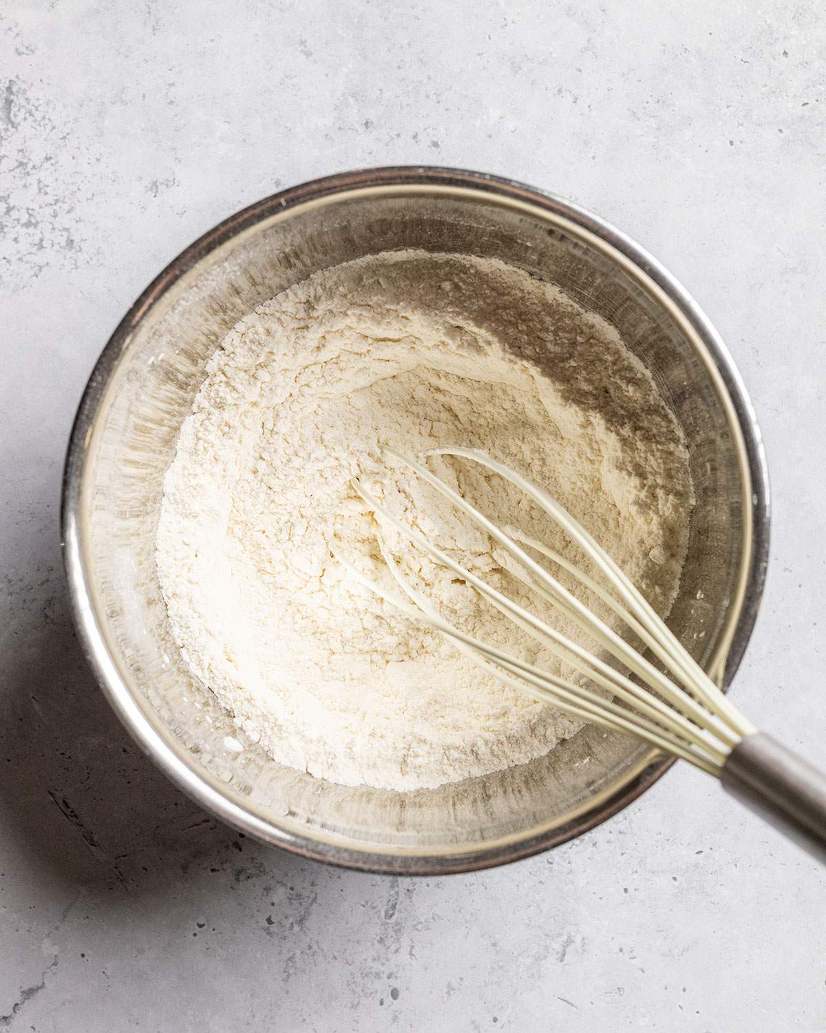 The dry ingredients for vegan kaiserschmarrn are whisked in a bowl.