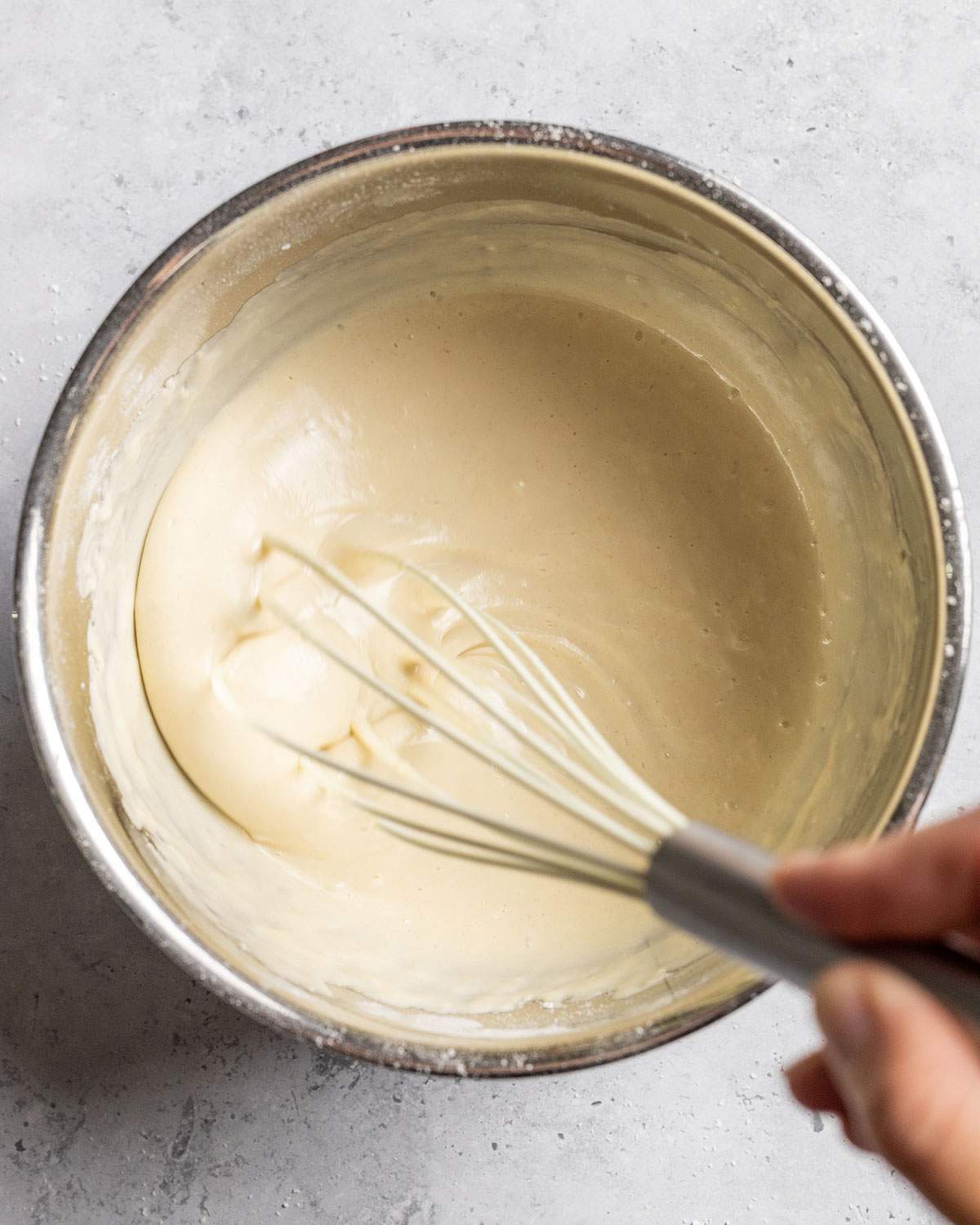 A hand is whisking vegan pancake batter.