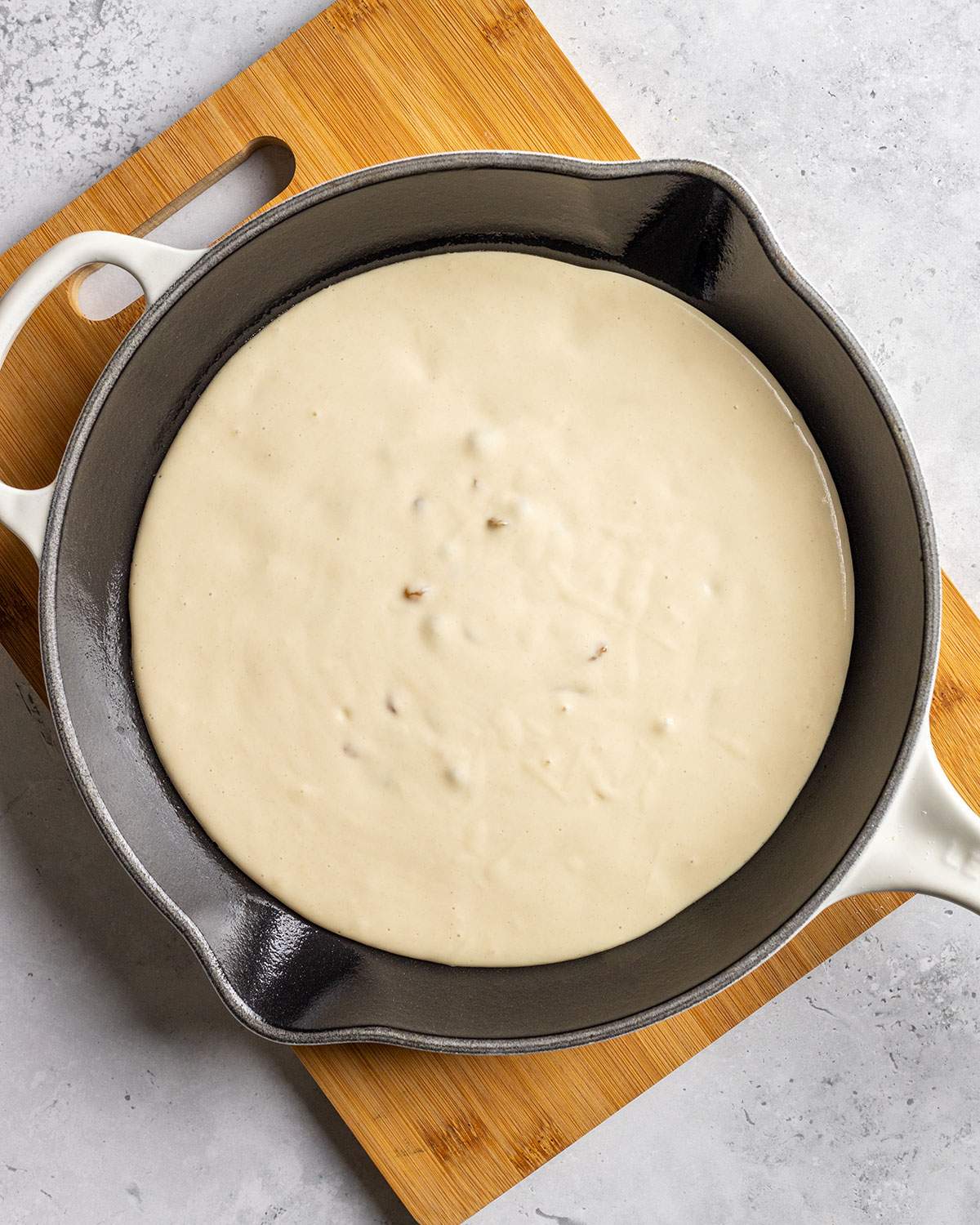 Vegan pancake batter has been poured into a round cast iron skillet.