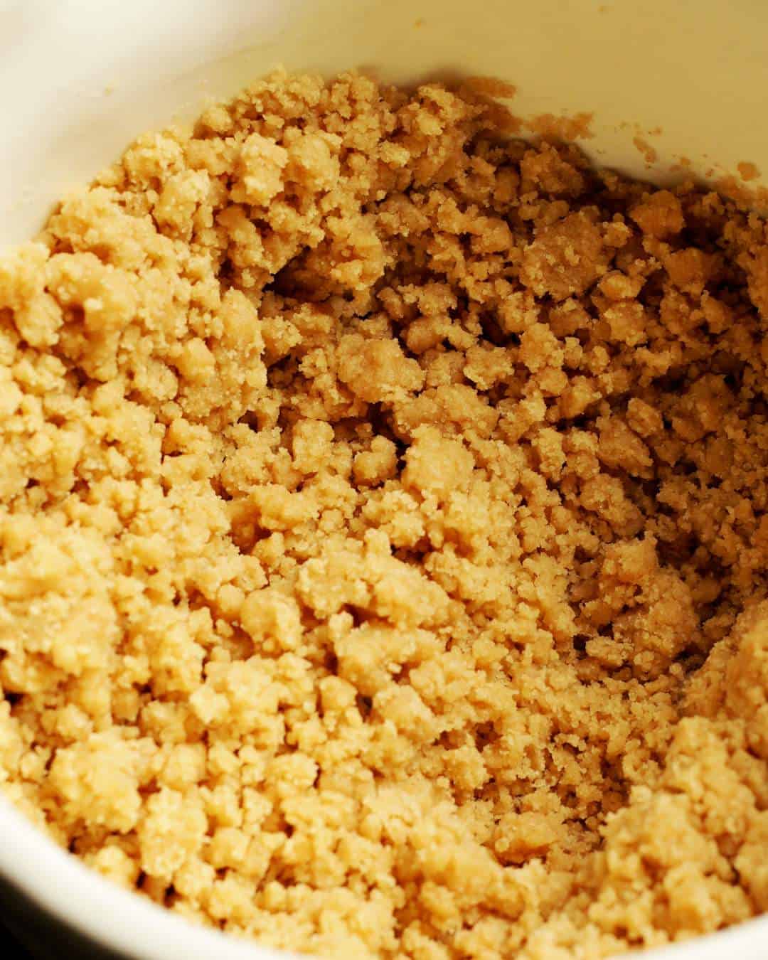 Crumbly vegan cinnamon cookie dough in a mixing bowl.