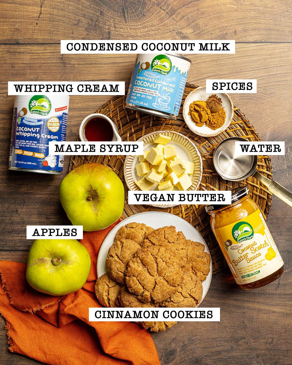 The ingredients for caramel apple parfait are arranged on a wooden table with labels on each ingredient.