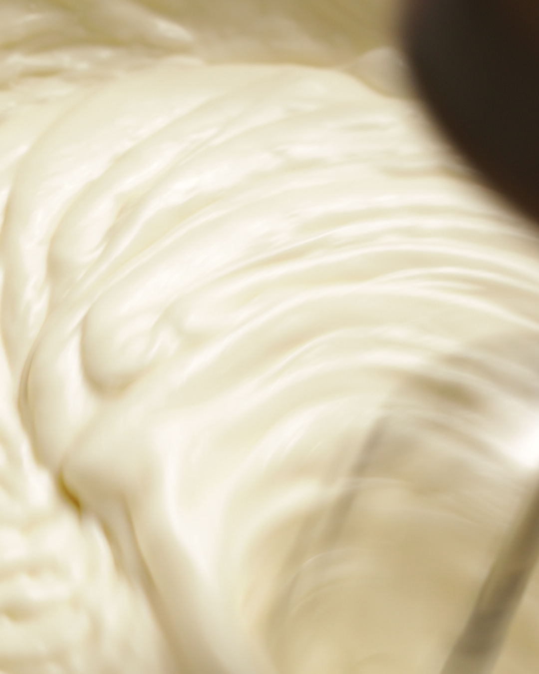 Coconut whipped cream and vegan butterscotch sauce are whipped in a mixing bowl.