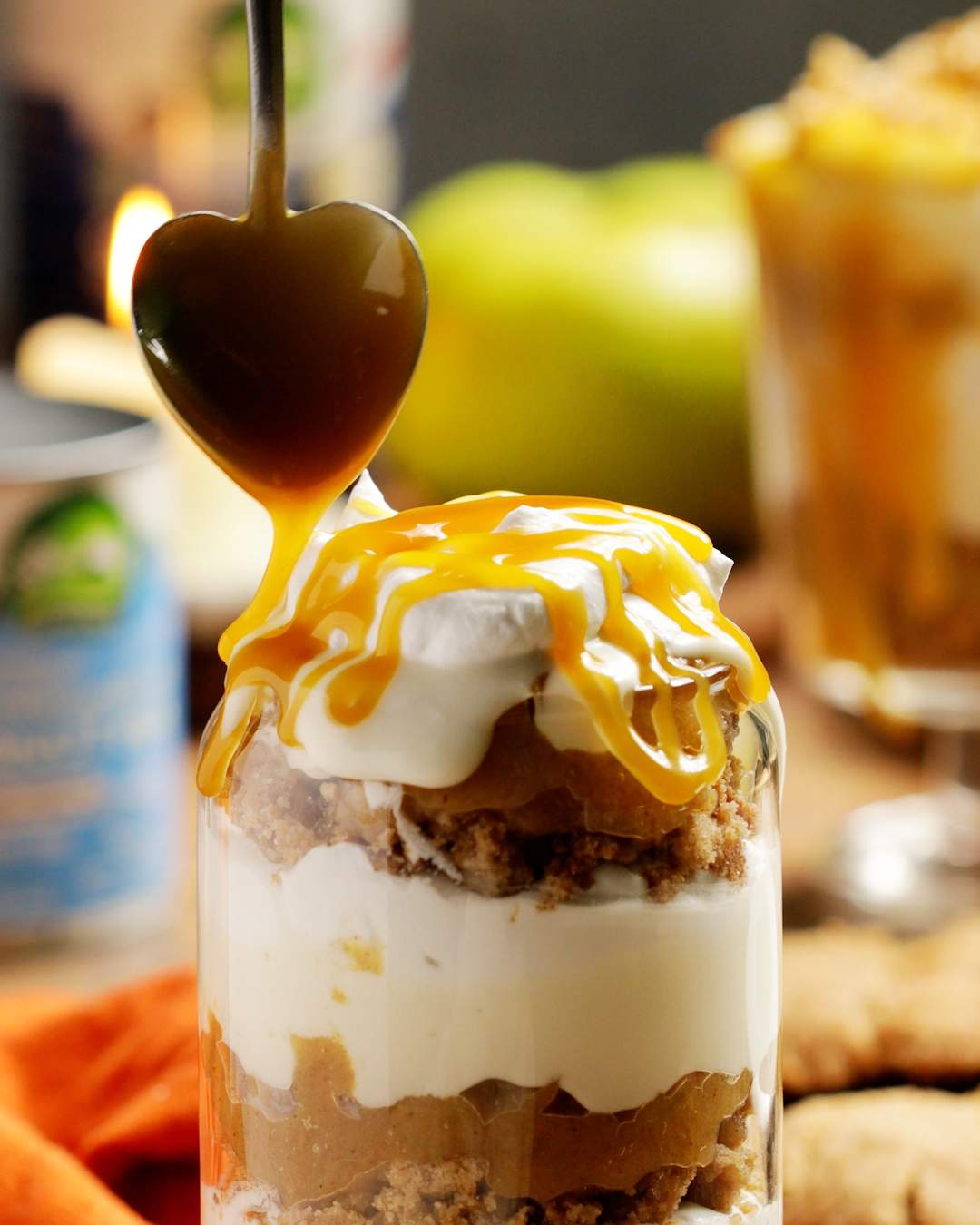 Butterscotch sauce is drizzling on top of the parfait from a spoon.