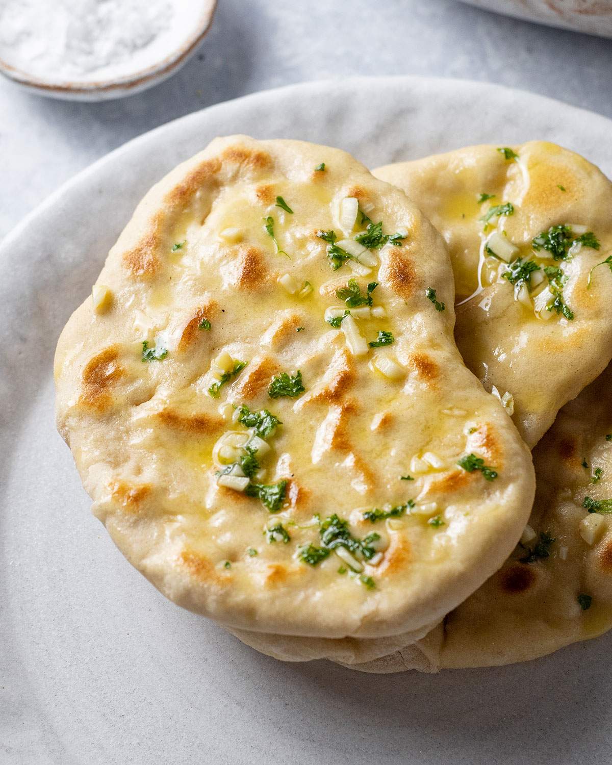 Three vegan naan breads are placed on top of each other on a serving plate.