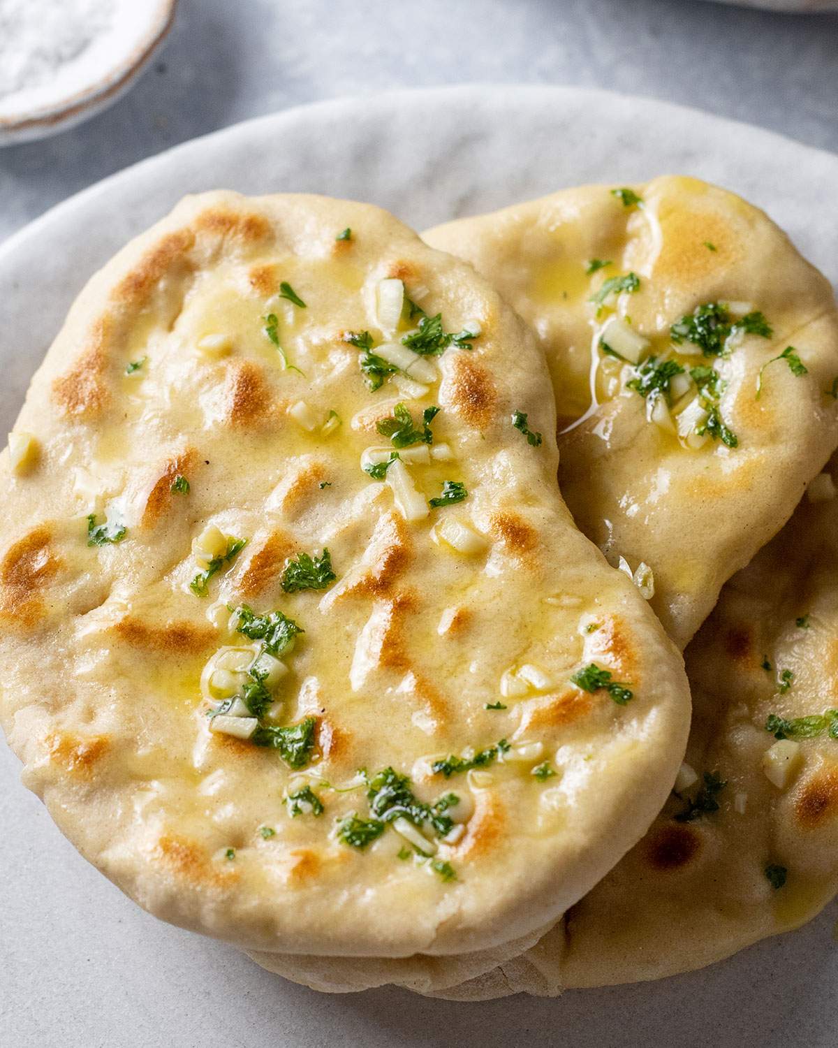 Three homemade vegan garlic naan breads are placed on a serving platter.