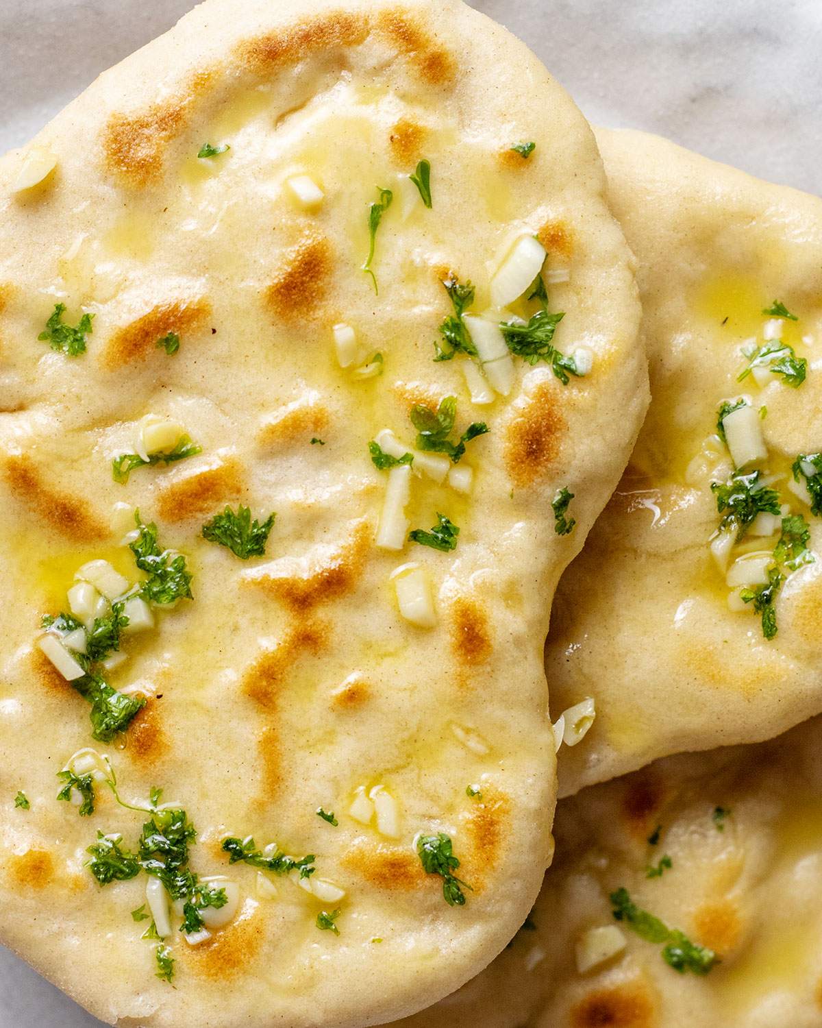 Vegan garlic naan bread is shown up close with fresh cilantro on top. 