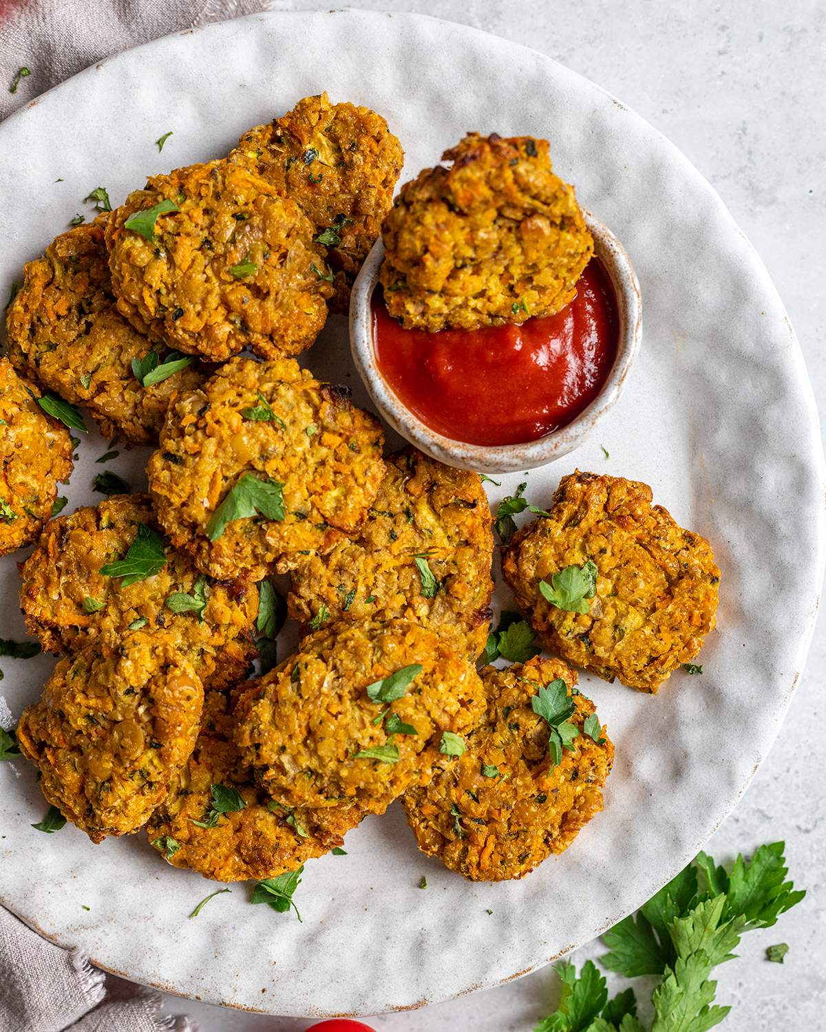 Vegan chickpea chicken nuggets are seen on a round serving platter with a small bowl of dip on the side.