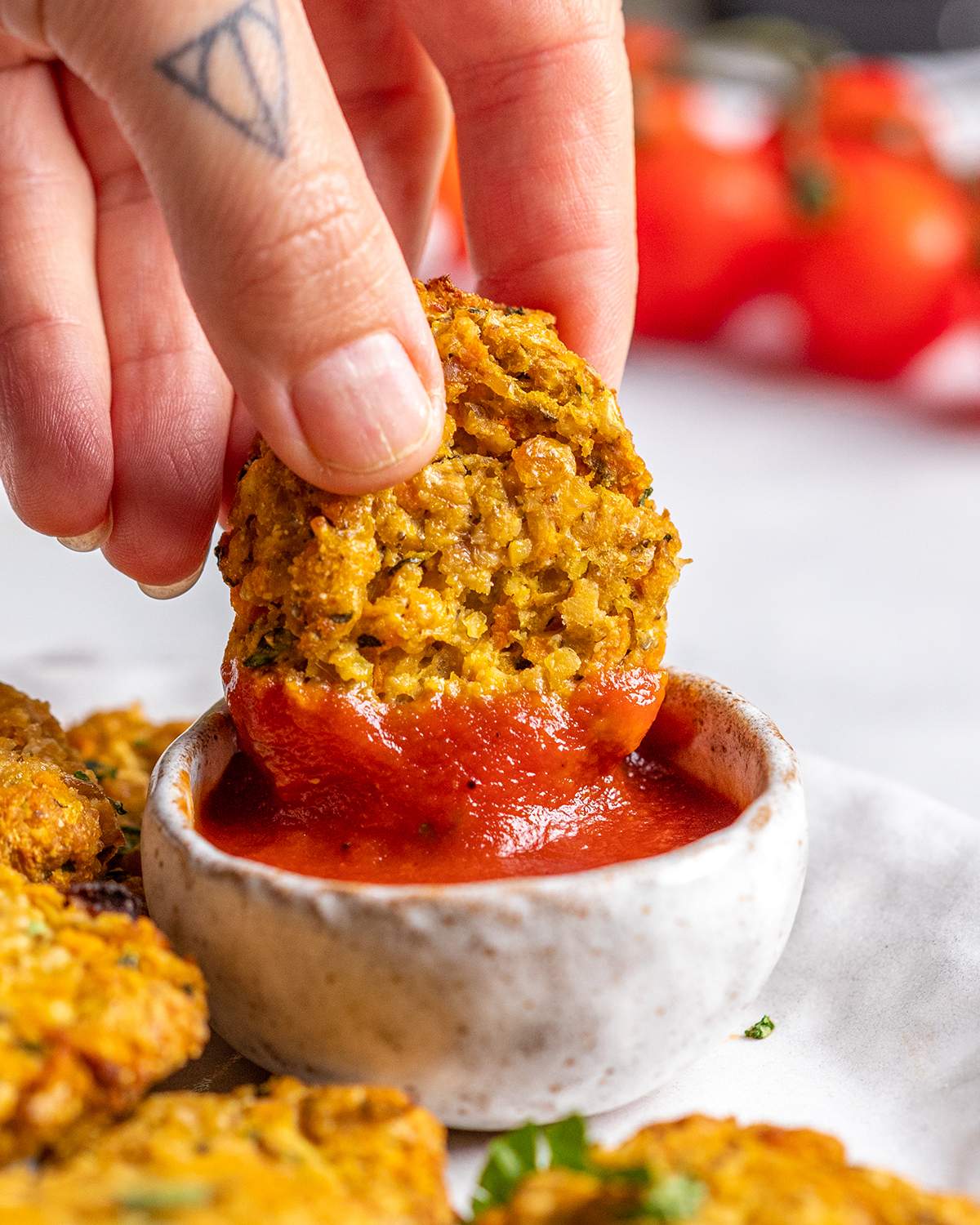 A hand is dipping a vegan chicken nugget into ketchup.