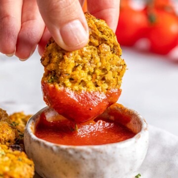 A hand is dipping a vegan gluten free chicken nugget into ketchup.