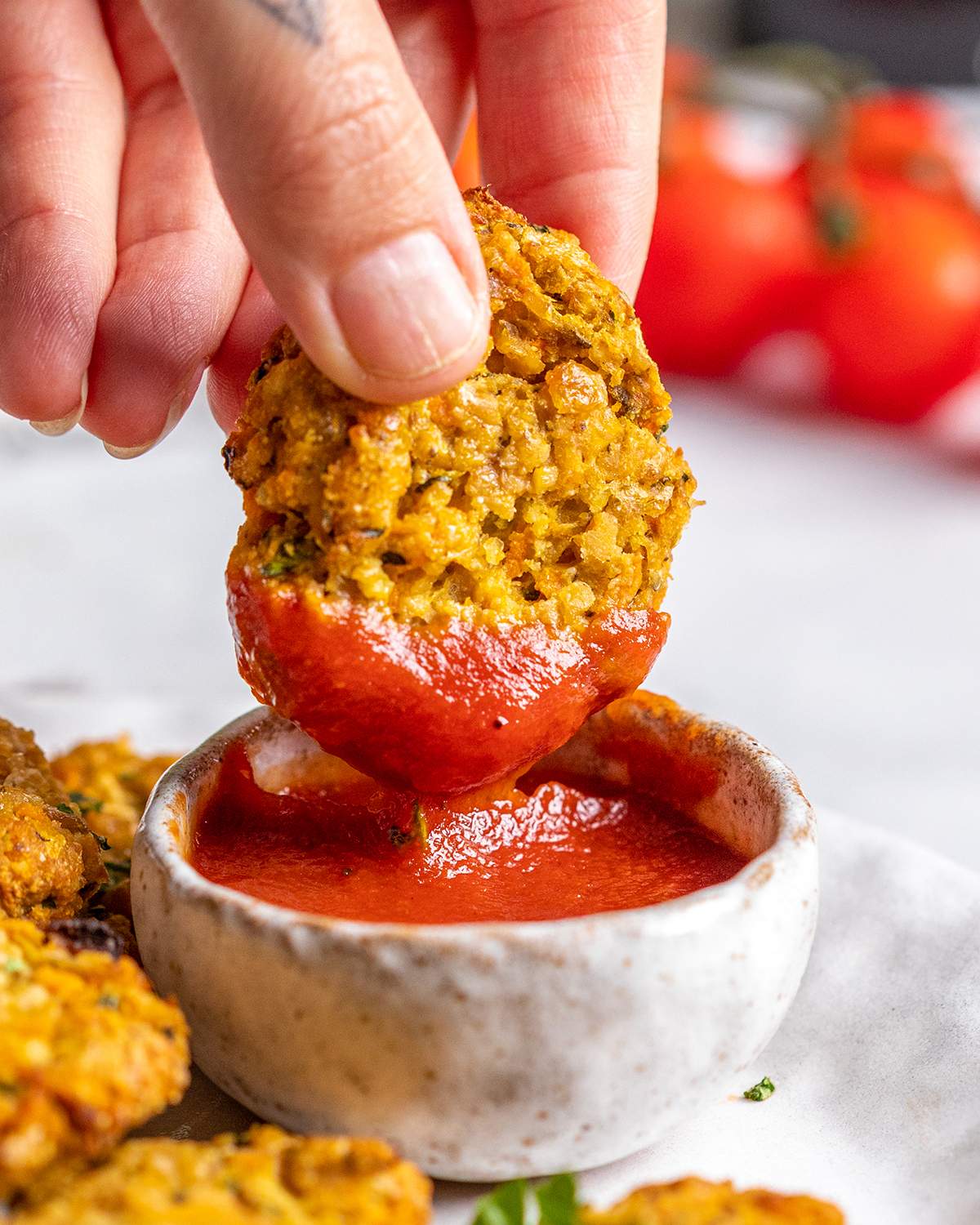 A hand is dipping a vegan gluten free chicken nugget into ketchup.