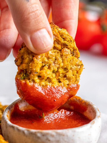 A hand is dipping a vegan gluten free chicken nugget into ketchup.